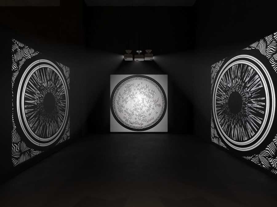 Symmetrical room with large circular graphic works facing one another and a spotlit piece at the end